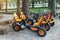 Many modern pedal toy cars for two person fo rent or sharing outdoors in city park, garden or forest. Healthy family outside sport