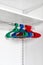 Many multicolored hangers on rod, on white wall background. Store concept, sale, design, empty hanger