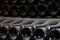 Many old dusty black champagne bottles, stacked in the wine cellar close up view