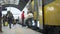 Many passengers with suitcases leaving train and walking on railway platform