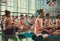 Many people breathing and making practice of meditation in simple yoga asana inside fitness club