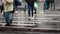 Many people cross the street on a pedestrian crosswalk during the rain . Legs close up