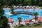 Many people rest on a hot summer day by the pool. Men, women, children swim in the pool and sunbathe on deckchairs