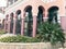 Many pink tall sturdy columns of the building of the eastern Arab Islamic building with arches and patterns and tropical plants