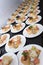 Many plates of appetizers being prepared in commercial kitchen, for an event, selective focus