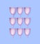 Many purple menstrual cups on light blue background, flat lay