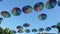 Many rainbow colour umbrellas hanging overhead on blue sky background