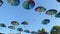 Many rainbow colour umbrellas hanging overhead on blue sky background