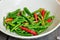 Many red and green Thai Chillis in plate on wooden table.