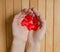 Many red hearts in women palms. Wooden background