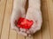 Many red hearts in women`s palms. Wooden background