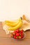 Many red strawberries on glass plate and bunch of bananas on wooden table top view