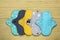 Many reusable cloth menstrual pads on yellow wooden table, flat lay