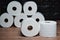 Many rolls of bathroom toilet paper on a wood and dark background
