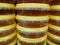 Many round containers of honey with a yellow lid. Front view.