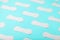 Many Sanitary pads on a blue background in the form of a diagonal pattern. Textured background all over the screen