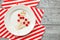 Many scattered toothpicks with a small red heart on a white plate and a striped festive napkin