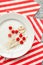 Many scattered toothpicks with a small red heart on a white plate and a striped festive napkin