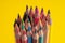 Many sharpened colored pencils laid out on a yellow background. Copyspace