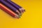 Many sharpened colored pencils laid out on a yellow background. Copyspace