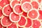 Many sliced fresh grapefruits as background