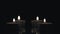 Many small flaming candles on black glass table