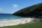 Many small people on a white beach with a mountain in the background. Archill Round Tour of Doogort Böll Cottage in Ireland.