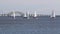 Many small sailboats sailing in a winter regatta passing the Great South Bay bridge on Long Island