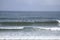 Many surfers sit and lie on their surfboards between breaking approaching waves on a beach in Portugal