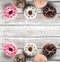 Many sweet donuts on an old wooden table, top view, space for text. Double mirror effect