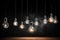 Many switched on electric light bulbs on a dark background.