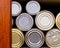 Many tin cans stacked on a pantry shelf in a row