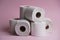 Many toilet paper rolls in a pile. Soft hygienic paper. Pink background
