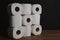 Many toilet paper rolls piled in a heap. Soft hygienic paper. Wooden table on black background