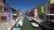 Many tourists viewing brightly colored houses in Burano island street, Venice