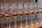 Many transparent crystal wine glasses with cognac stand in row on the brown wooden shelves of the rack. Side view. The concept of