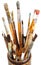 Many used artistic paintbrushes in wooden cup