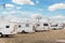 Many white modern campervan recreational motor home vehicles parked in row at camper park site Magdeburg city against