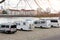 Many white modern campervan recreational motor home vehicles parked in row at camper park site Magdeburg city against