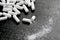 Many white pills on black background. Broken pill and white dust around.White tablets, medication