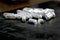 Many white pills on black background. Broken pilll and spilled dust. White tablets, medication