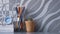 Many wooden pencils in glass jar, little alarm clock on stacked books with green cactus in clay pot on tabletop with gray tile