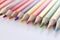 Many wooden sharp multicolored pencils lying on white background