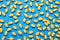 Many yellow dragee candies on blue background, flat lay