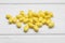 Many yellow dragee candies on white wooden table, closeup