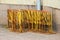 many yellow fences stand at the ready against the wall of the building. an object that isolates and guides a crowd of