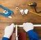 Manâ€™s hands solder white plastic pipes to assemble a water pipe in a country house