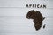 Map of the Africa made of roasted coffee beans laying on white wooden textured background