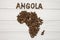 Map of the Angola made of roasted coffee beans laying on white wooden textured background