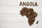 Map of the Angola made of roasted coffee beans laying on white wooden textured background